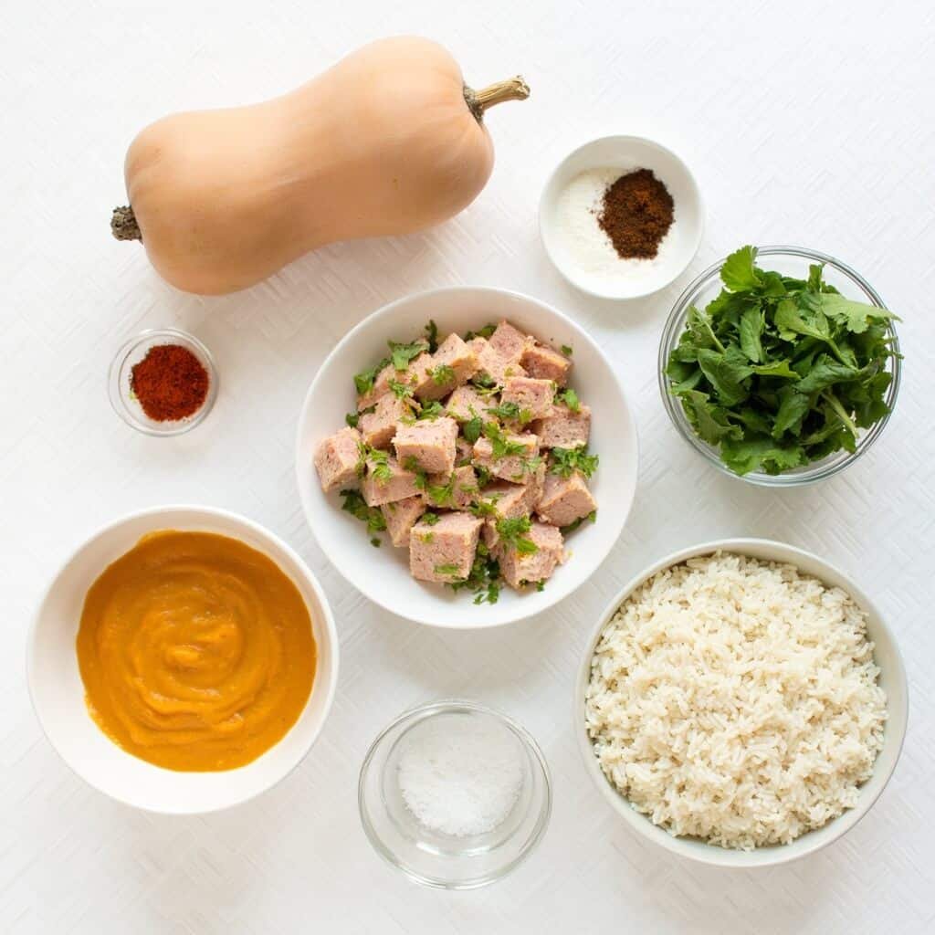 Pumpkin puree, canned tuna, rice, and assorted chopped vegetables laid out as cooking ingredients.